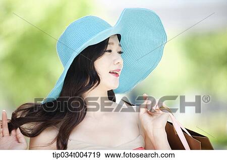 Stock Photo - close up shot of a woman in turquoise hat holding shopping bags. Fotosearch