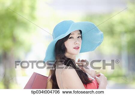 Stock Photograph - close up shot of a woman in turquoise hat with shopping bags . Fotosearch