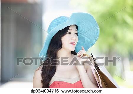 Stock Photograph - close up shot of a woman in turquoise hat holding shopping bags. Fotosearch
