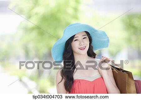 Stock Image - close up shot of a woman with hat holding shopping bags . Fotosearch