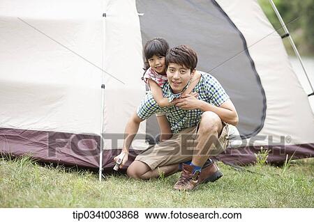 daughter hugging from back of her father while he builds a tent View Large Photo Image Stock Photo - daughter hugging from back of her father while he builds a tent. Fotosearch
