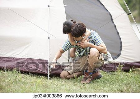 daughter hugging from back of her father while he builds a tent View Large Photo Image Stock Photograph - daughter hugging from back of her father while he builds a tent. Fotosearch