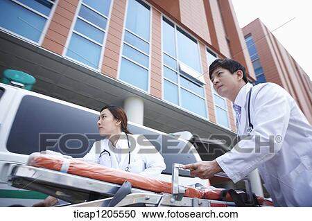 Stock Image - doctors moving a carrier ungently into the hospital. Fotosearch
