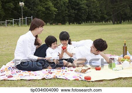 Stock Image - family having a picnic on a picnic blanket. Fotosearch