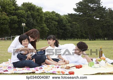 Stock Photo - family having a picnic on a picnic blanket. Fotosearch
