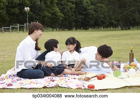 Stock Photo - family having a picnic on a picnic blanket. Fotosearch