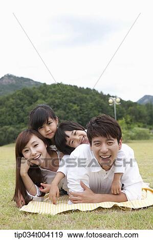 Stock Photo - family lying on their stomach posing at camera. Fotosearch
