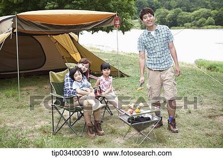 Stock Image - family posing at camera while enjoying their camp. Fotosearch