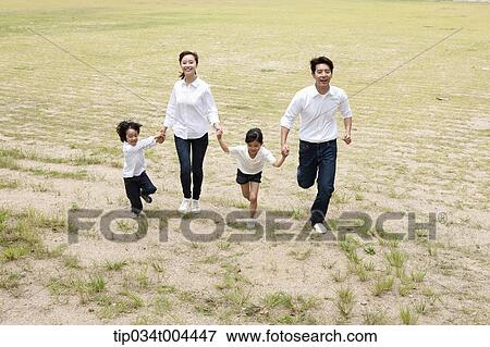 Stock Photo - Family running hand in hand on a field. Fotosearch