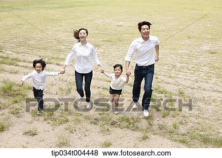 Stock Photo - Family running hand in hand on a field. Fotosearch