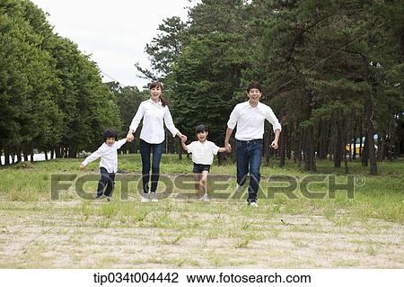 Stock Image - Family running hand in hand on grass. Fotosearch