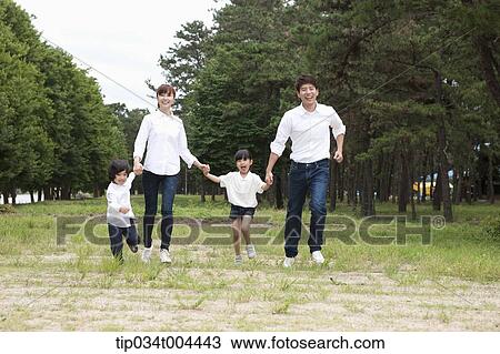 Family running hand in hand on grass View Large Photo Image Stock Image - Family running hand in hand on grass. Fotosearch