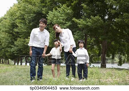 Stock Image - Family running hand in hand on grass. Fotosearch