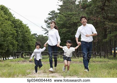 Stock Photography - Family running hand in hand on grass. Fotosearch