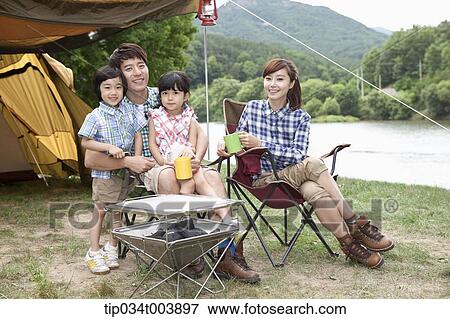 Stock Photo - family sitting on camping chairs posing at camera. Fotosearch