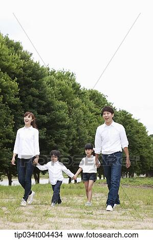 Family walking hand in hand on grass View Large Photo Image Picture - Family walking hand in hand on grass. Fotosearch