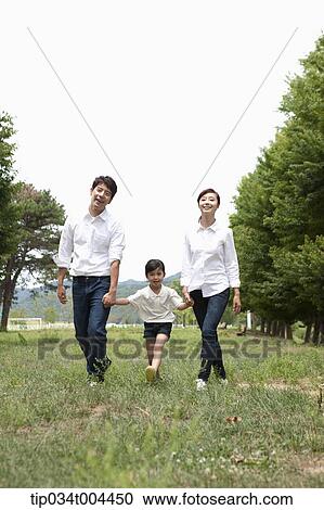 Family walking hand in hand on grass View Large Photo Image Stock Image - Family walking hand in hand on grass . Fotosearch