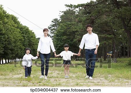Family walking hand in hand on grass View Large Photo Image Stock Photo - Family walking hand in hand on grass. Fotosearch