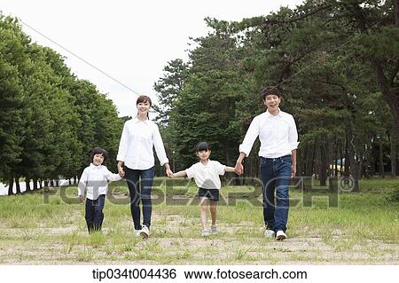 Stock Photograph - Family walking hand in hand on grass. Fotosearch