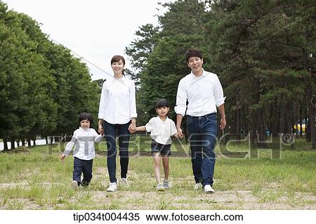 Stock Photography - Family walking hand in hand on grass. Fotosearch