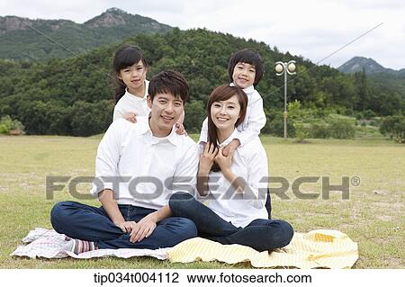 Stock Image - family wearing jeans posing at camera in picnic. Fotosearch