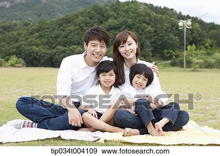 Stock Photo - family wearing jeans posing at camera in picnic. Fotosearch