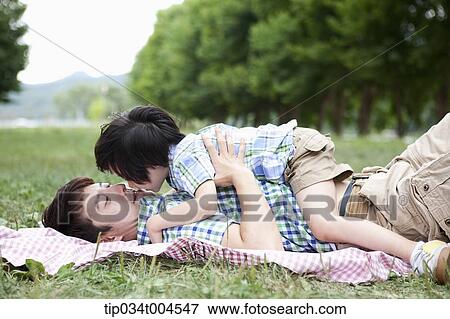 Stock Photo - father and son kissing while lying on a picnic blanket . Fotosearch