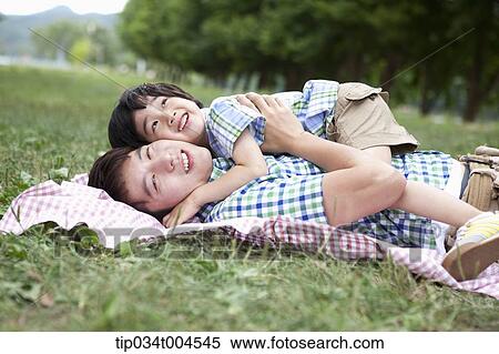 Stock Photography - father lying on a picnic blanket with a son lying on him. Fotosearch