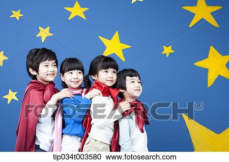 Stock Image - four kids wearing superman capes standing in a line. Fotosearch