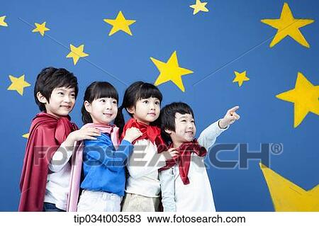 Stock Image - four kids wearing superman capes standing in a line in front of a blue wall full of stars. Fotosearch