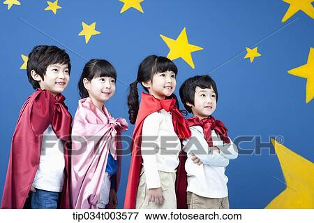 Stock Photo - four kids wearing superman capes standing in a line in front of a blue wall full of stars. Fotosearch
