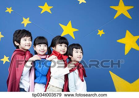 Stock Photo - four kids wearing superman capes standing in a line in front of a blue wall full of stars. Fotosearch