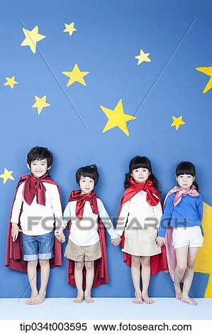Stock Photography - four kids wearing superman capes standing in a line with their backs on a wall. Fotosearch