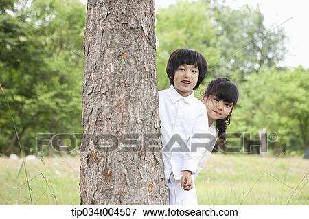 Stock Photo - kids hiding behind a tree. Fotosearch