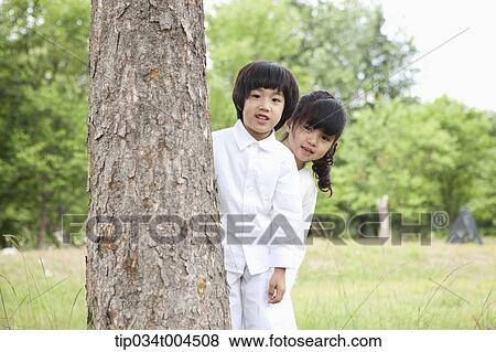 Stock Photo - kids hiding behind a tree. Fotosearch