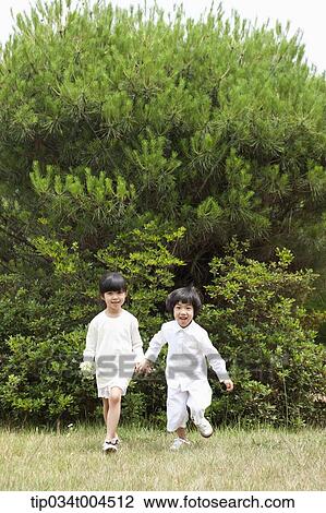 Stock Image - kids running on grass hand in hand . Fotosearch