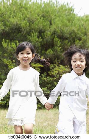 Stock Image - kids running on grass hand in hand . Fotosearch