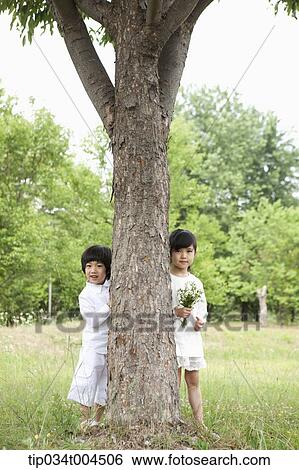 Stock Photograph - kids standing behind a tree. Fotosearch