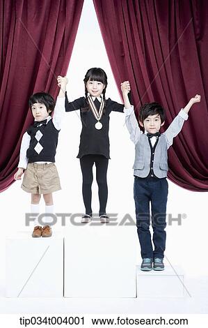 Stock Image - kids standing on podium raising their hands . Fotosearch