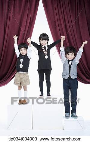 Stock Image - kids standing on podium raising their hands . Fotosearch
