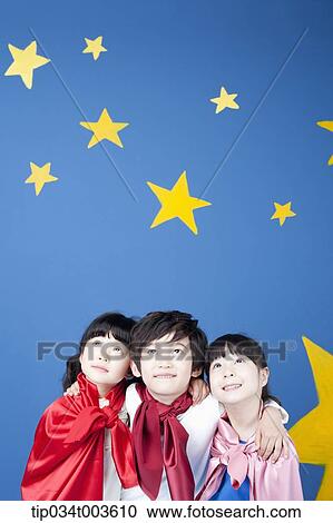 Stock Image - kids wearing superman capes looking up high. Fotosearch
