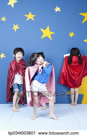 Stock Image - kids wearing superman capes playing hide and seek. Fotosearch