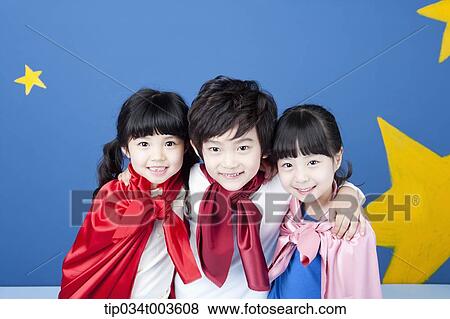 Stock Photo - kids wearing superman capes smiling in front of a blue wall full of stars. Fotosearch
