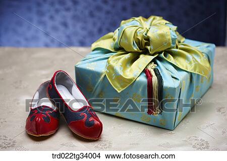Picture - Korean traditional shoes next to a package wrapped in traditional wrap . Fotosearch