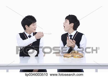 male student giving the other identical male student a spoon of rice View Large Photo Image Stock Image - male student giving the other identical male student a spoon of rice . Fotosearch