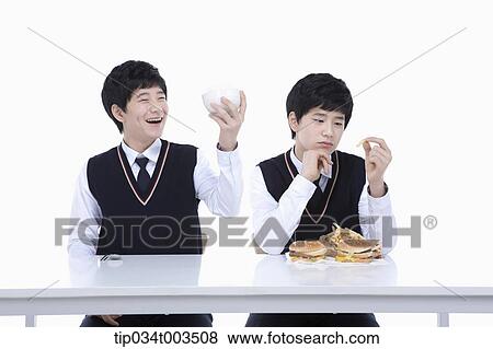 Stock Photo - male student happily holding a rice bowl while the other identical student is holding French fry. Fotosearch