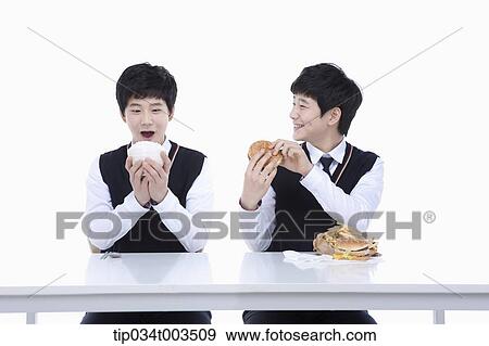 male student happily holding a rice bowl while the other identical student is having a burger View Large Photo Image Stock Photo - male student happily holding a rice bowl while the other identical student is having a burger. Fotosearch