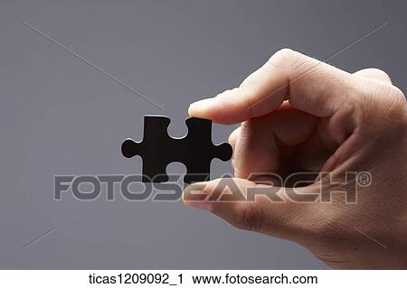 Stock Image - man holding a piece of puzzle. Fotosearch