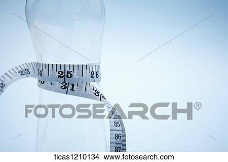 measurement tape surrounding an empty bottle View Large Photo Image Picture - measurement tape surrounding an empty bottle. Fotosearch