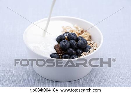 Picture - milk being poured in to a bowl of cereal. Fotosearch